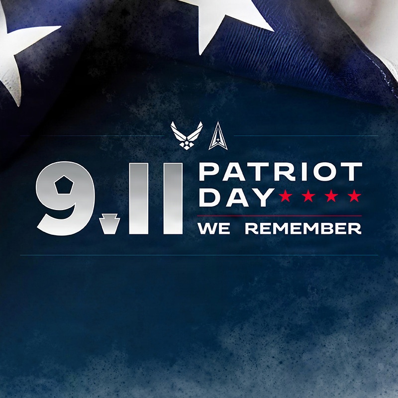 This is a commemorative graphic for 9/11 Patriot Day featuring the text '9.11 PATRIOT DAY - WE REMEMBER' on a dark navy blue background. The image includes military branch insignia and an American flag partially visible in the upper portion. It appears to be an official memorial graphic, likely produced by or for the U.S. Air Force and U.S. Space Force.