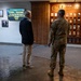 Three individuals are standing in a hallway at Air Force Special Operations Command (AFSOC), viewing a memorial wall displaying Air Force Cross and Silver Star recipients. A digital sign identifies the visit as 'CODEL-ROGERS' welcoming The Honorable Mike Rogers, Chairman of the House Armed Services Committee. One person is in military camouflage uniform while the other two are in civilian attire.