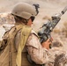 A soldier wearing desert camouflage uniform and tactical gear is positioned behind rocky cover in an arid environment. The individual, identified by a name tape reading 'FRANCO', is holding an assault rifle equipped with a scope and suppressor. The setting and equipment suggest a military training exercise or operational deployment in a desert terrain.