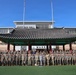 A large group of military personnel, predominantly in camouflage uniforms, pose for a formal group photograph in front of a traditional Korean pavilion (정자/jeongja) structure. The setting appears to be a military installation, with a building labeled 'Freeman Hall' visible in the background along with a partial 'WARRIOR' sign. The combination of the Korean architectural element and mixed military uniforms suggests a joint US-South Korean military event or exchange program.
