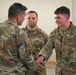 Three U.S. Air Force personnel in OCP (Operational Camouflage Pattern) uniforms are engaged in a handshake interaction, likely a formal recognition or greeting ceremony. The airman on the right, identified by the name tape 'SEGREST,' is shaking hands with a senior individual whose back is to the camera, while a third airman observes from the background. The setting appears to be inside a military hangar or facility.