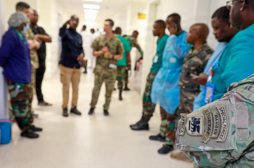 The image shows a group of military and medical personnel gathered in what appears to be a hospital corridor. In the foreground, a soldier's arm is clearly visible displaying patches reading 'Special Forces,' 'Ranger,' 'SETAF,' and 'Africa.' The scene suggests a military medical exchange, training visit, or joint operation between U.S. Special Forces and local military/medical staff.