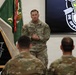 A U.S. Army senior non-commissioned officer named Rivas is addressing a group of soldiers in a formal military setting. The backdrop features the U.S. Army Special Forces insignia and motto 'De Oppresso Liber,' indicating this is a Special Forces unit gathering. The speaker appears to be conducting a briefing or address to assembled personnel.