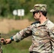 Two U.S. Army soldiers are at an outdoor firing range. The soldier facing the camera, identified by name tape as 'PETERSEN,' holds the rank of Major (gold oak leaf) and wears a Ranger tab. He appears to be handing or receiving a small object, likely a magazine or ammunition, from the other soldier.