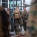 Several military personnel in camouflage uniforms are gathered near the door of a bus or military transport vehicle. The soldiers appear to be in the process of boarding or preparing to depart. At least one soldier is wearing a tan tactical backpack with a visible name tape reading 'SAMUEL'.