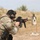 Law Enforcement Agency Conducts LEWTAQ at Fort Hood A military or law enforcement personnel is engaged in a live-fire shooting exercise at an outdoor range. The shooter is in a crouched stance aiming an M4-style carbine rifle at a silhouette target downrange. A spent brass casing is visibly ejecting from the weapon, indicating the moment of firing.