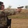 Law Enforcement Agency Conducts LEWTAQ at Fort Hood A U.S. Army soldier in MultiCam (OCP) camouflage uniform is firing a pistol at an outdoor shooting range. A spent brass casing is visibly ejecting from the firearm mid-shot. The soldier is wearing proper hearing and eye protection, indicating a controlled training or competition environment.