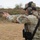 Law Enforcement Agency Conducts LEWTAQ at Fort Hood A U.S. Army Military Police soldier named Taylor is firing a pistol at a shooting range. The soldier is wearing full MultiCam (OCP) uniform with a plate carrier vest, hearing protection, and a patrol cap. A second individual is visible behind the shooter, appearing to provide oversight or instruction.