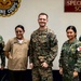 Five military personnel pose for a group photo in front of a 'Specialized School' sign and a Philippine Marine Corps emblem. The group includes members from both the Philippine Marine Corps/Navy and the U.S. Navy/Marine Corps, suggesting a joint military engagement or training event. The setting appears to be inside a Philippine military facility.