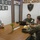 Three individuals are seated around a conference table in a Marine Corps Medical Service office. The meeting involves two military personnel in camouflage uniforms and one civilian in a white t-shirt. The setting appears to be an official military medical facility, likely in the Philippines based on visible insignia.