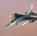 An F-16 Fighting Falcon jet fighter is photographed in flight from an aerial perspective, likely from a tanker or accompanying aircraft. The aircraft bears tail code 'AV' and serial number '413', indicating it belongs to the 31st Fighter Wing based at Aviano Air Base, Italy. The aircraft is flying over an arid desert landscape and is armed with multiple air-to-air and air-to-ground munitions.