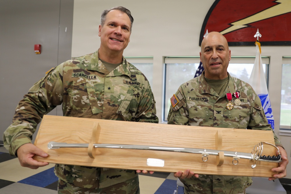 Two U.S. Army soldiers in MultiCam/OCP camouflage uniforms are posing together while holding a ceremonial saber mounted on a wooden display plaque. The soldier on the left is identified by name tape as 'SCARCELLA' and wears a Brigadier General star insignia, while the soldier on the right is identified as 'FARABAUGH' and wears a Colonel eagle insignia along with multiple medals including what appears to be a Meritorious Service Medal. This appears to be a military retirement or award ceremony presentation.