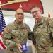 Two U.S. Army soldiers pose together in a formal military ceremony setting. The soldier on the left, identified by name tape as 'FARABAUGH,' is wearing a medal (appears to be a Meritorious Service Medal or similar decoration) and holding a small blue case, suggesting a recent award presentation. The soldier on the right, identified as 'VANCAMP,' displays a two-star general rank insignia on his collar.