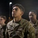 A group of U.S. Army soldiers in Operational Camouflage Pattern (OCP) uniforms are gathered outdoors at night under artificial lighting. The central figure, identified by name tape as 'SIERRA,' is standing at attention or listening attentively. A unit patch on the right sleeve reads 'Toujours Prêt,' associated with the 2nd Armored Cavalry Regiment.