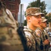 The image shows at least three U.S. military personnel in MultiCam (OCP) camouflage uniforms standing in formation on an urban street. The soldiers are wearing tactical gear including plate carriers and are equipped with weapons. They appear to be on a domestic deployment or security detail in a city environment.