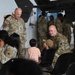 The image shows a military gathering inside what appears to be an aircraft hangar, with U.S. Army soldiers in OCP (Operational Camouflage Pattern) uniforms interacting with civilians including children. A senior officer identified by the name tape 'BLANCHARD' and a general officer star is visible speaking with a soldier who is engaging with two young boys. The setting suggests a family day, unit ceremony, or pre/post-deployment event.