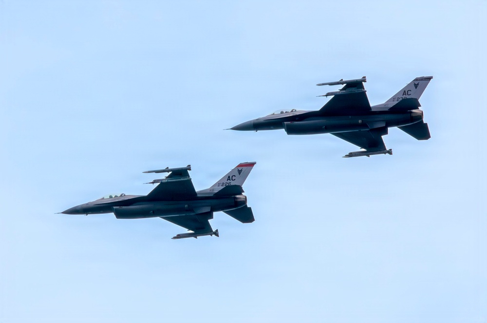 Two F-16 Fighting Falcon jet fighters fly in close formation against a pale blue sky. Both aircraft bear the tail code 'AC' and serial numbers 226 and 236, indicating they belong to the New Jersey Air National Guard's 177th Fighter Wing based at Atlantic City (AC). The aircraft are equipped with visible air-to-air missiles and external fuel tanks or munitions pods.