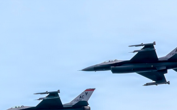 Two F-16 Fighting Falcon jet fighters fly in close formation against a pale blue sky. Both aircraft bear the tail code 'AC' and serial numbers 226 and 236, indicating they belong to the New Jersey Air National Guard's 177th Fighter Wing based at Atlantic City (AC). The aircraft are equipped with visible air-to-air missiles and external fuel tanks or munitions pods.