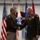Col. Finch Concludes Distinguished Career, Leaves Lasting Legacy as Command State Chaplain Two U.S. Army officers in dress green uniforms are shaking hands during what appears to be a formal military ceremony. The officer on the left wears an 82nd Airborne Division patch, while the officer on the right displays multiple medals and ribbons along with a chaplain's cross insignia. Several military and U.S. flags are displayed in the background.