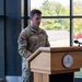 A U.S. Army soldier with the name tape 'BEAUREGARD' is speaking at a wooden podium inside a modern building with large windows. The podium bears a seal that appears to read 'Army Mountain Warfare School.' The setting suggests an official military ceremony or briefing.