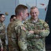 A group of U.S. Army soldiers in OCP (Operational Camouflage Pattern) uniforms are gathered inside what appears to be a military fitness facility with a rock climbing wall in the background. The soldier on the right, identified by his name tape as 'TANGUAY,' stands with arms crossed and is smiling while engaged in conversation. Several other soldiers are visible in the background, including individuals with name tapes 'ROS__' and 'DIERPA.'