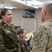 A U.S. Army female soldier in Army Service Uniform (ASU) is engaged in a face-to-face conversation with a male soldier wearing Operational Camouflage Pattern (OCP) uniform. The female soldier displays the rank of Sergeant (E-5) and several service ribbons on her dress uniform. The setting appears to be an indoor military classroom or conference room.