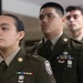 Four U.S. Army soldiers in Army Service Uniforms (ASUs) are standing in formation, appearing to be at attention or in a formal ceremony. The foreground soldier, identified by a name tape reading 'TURNER', is a female soldier wearing ribbons, badges, and unit patches. The soldiers behind her are male and also display various awards, patches, and insignia on their dress uniforms.
