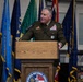 A senior military officer in U.S. Army dress greens uniform is speaking at a podium bearing the Georgia National Guard seal. The setting appears to be an official military ceremony or briefing, with multiple flags displayed in the background. The officer is wearing numerous medals, ribbons, and insignia indicating high rank and extensive service.