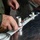 U.S. Marines and Thailand Mine Action Center participate in Deployed for Training Bilateral EOD Exercise A person wearing an olive/green work shirt is assembling or disassembling mechanical components on a dark marble or stone surface. Multiple cylindrical metal parts, rings, and fittings are laid out in a row on a white strip or rail. A second person is partially visible in the background, appearing to observe.