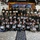 U.S. Marines and Thailand Mine Action Center participate in Deployed for Training Bilateral EOD Exercise A large group of military personnel from Thailand and the United States pose together for a group photo holding certificates at what appears to be a bilateral training exercise completion ceremony. The backdrop displays a banner reading 'DEPLOY FOR TRAINING BILATERAL EOD EXERCISE' along with Thai and American flags and unit insignia. Participants are arranged in multiple rows under an open-air pavilion.