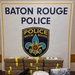 This is an official law enforcement evidence display photograph taken by the Baton Rouge Police Department. The image shows seized contraband items arranged on a table in front of a Baton Rouge Police Department backdrop. This appears to be a standard press/public information photo documenting a drug seizure.