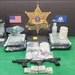 This is an official law enforcement evidence display photograph from the East Baton Rouge Parish Sheriff's Office Narcotics Division. The image shows seized contraband, weapons, currency, and drug paraphernalia arranged in front of the agency's official insignia. This type of photograph is standard procedure for documenting narcotics seizures.