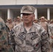 A senior officer of the Marina de Guerra del Perú (Peruvian Navy) identified by name tape as 'J. Navarro' stands at attention during what appears to be a military formation or ceremony. He wears a camouflage uniform with rank insignia on his cap and chest, along with a naval warfare qualification badge. Behind him, rows of uniformed military personnel are visible, along with what appears to be a U.S. Marine in woodland MARPAT camouflage on the left.