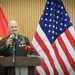 A senior U.S. Army general officer is speaking at a podium during an official press conference or diplomatic event. He is flanked by the American flag and what appears to be the Angolan flag, suggesting a bilateral military or diplomatic engagement. A microphone labeled 'TPA' (Televisão Pública de Angola) is visible at the podium.