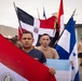 A group of men in military or athletic attire are gathered outdoors holding multiple Latin American national flags. The foreground prominently features the flags of Paraguay and Honduras, with the Dominican Republic flag visible in the background along with other unidentified flags. The setting appears to be a military base or training facility, suggesting a multinational military exercise or ceremony.