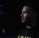 A young man is photographed in profile at night, illuminated by a light source from the right side. He is wearing a black shirt with yellow 'ARMY' lettering visible at the bottom of the frame. His face appears to be perspiring, suggesting recent physical activity.