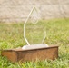 A clear glass/crystal award trophy in a diamond shape sits on a wooden base placed on grass outdoors. The award is from the Inspector General of the Marine Corps, specifically the 'General Friedrich von Steuben Award 2026,' presented to the 2d Marine Logistics Group. The engraving recognizes the unit for demonstrating the highest level of Marine Corps efficiency, integrity, and institutional readiness.