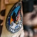 The image shows a military or security force patch attached via velcro to a desert camouflage uniform or vest. The patch references 'TCHAD' (French for Chad) and includes the acronym 'DGSAT', along with an eagle motif and what appears to be an American flag, suggesting a joint or advisory mission in Chad. The patch is circular with a banner at the bottom and stars around the border.