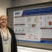 A woman named Allison Hoke stands beside a scientific research poster at what appears to be an academic or military health conference. The poster is titled 'Impact of Microgravity on Osteoblast Cells Treated by Osteoinductive Agents: A Multi-Omics Analysis' and is affiliated with the Defense Health Agency (DHA). She is wearing a name badge and posing next to her research presentation.