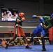 Two boxers are competing in a boxing ring during what appears to be a military boxing event called 'Phantom Warriors vs Phantom Lethal.' One boxer wearing red gear and 'Title Boxing' shorts is exchanging punches with an opponent in blue gear and a green shirt. A crowd of spectators watches from ringside, and a scoreboard/display screen in the background shows fighter profiles labeled 'Webb' and 'Jackson' in the Middleweight category.