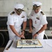 Two U.S. Navy Commanders in white dress uniforms are cutting a ceremonial cake with swords at a Change of Command ceremony for MSRON-1. The cake bears the text 'MSRON-1 CHANGE OF COMMAND' and 'CONGRATULATIONS CDR LOVITT AND CDR GABBARD,' along with a U.S. Navy emblem. Both officers display rank insignia, ribbons, and warfare qualification badges consistent with Commander (O-5) grade.