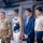 Sgt. Maj. Antonio Acevedo Promotion Ceremony Four individuals stand in front of a military helicopter, likely inside a hangar. One person on the left is wearing U.S. Army camouflage (OCP/MultiCam) uniform, while the other three are dressed in civilian attire. The setting and posture suggest a formal military ceremony or family recognition event.
