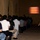 Mike Company Receiving A female Marine Corps drill instructor or staff sergeant stands at attention while overseeing a large group of seated recruits or civilians attending a briefing. A projected presentation titled 'Uniform Code of Military Justice' is displayed on a screen at the front of the room. The setting appears to be a military installation, likely during an orientation or processing event.