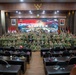 A large group of military personnel from multiple nations pose for a group photograph in a formal conference room. The backdrop displays a banner reading 'STAFFEX - Super Garuda Shield Exercise 2026,' indicating this is a joint military staff exercise. Indonesian and American flags are visible alongside the Indonesian national emblem (Garuda Pancasila), suggesting a bilateral or multinational military cooperation event.