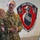 Polish General Piotr Trytek Strengthens Alliance During 12th CAB Visit Two military personnel are engaged in a briefing or discussion near a whiteboard with written notes. One soldier wears a US Army uniform with the name tape 'BILLMIRE' and Sergeant rank insignia, while the other wears a Polish military camouflage uniform with a Polish flag patch. They are standing in front of a unit insignia mural reading 'GUNSLINGERS' with the motto 'NO FRIEND NO WORSE ENEMY'.