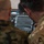 Polish General Piotr Trytek Strengthens Alliance During 12th CAB Visit Two military personnel in different camouflage uniforms are viewing a tactical display screen showing what appears to be an infrared or thermal imaging feed of terrain. The screen interface includes multiple control buttons and overlays consistent with a drone ground control station or targeting system. One individual appears to be pointing at or operating the display.