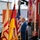 Katterbach Community and German Partners Commemorate 9/11 with Memorial Run and Ceremony A man in a blue suit stands at attention beside a row of ceremonial flags including the German flag, the American flag, and what appears to be a regional or organizational flag with red and yellow colors. The setting appears to be an outdoor ceremony at a fire station or emergency services facility, with a red fire truck visible on the right side. A firefighter helmet is visible on the ground in the foreground.