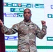 A U.S. Army officer with the name tag 'CLARK' and three stars on his chest (indicating the rank of Lieutenant General) is delivering a presentation on stage. He is gesturing with both hands while speaking in front of a large projected slide showing a military exercise schedule. The slide references various joint military exercises including 'Keen Sword,' 'Resolute Dragon,' 'North Wind,' and 'Keen Edge,' with flags indicating multinational participation.