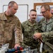 Three military personnel from different branches — U.S. Air Force and U.S. Navy — are gathered around a workbench examining tools and equipment. The individuals are identifiable by their name tapes and branch insignia, with 'WESTERN' and 'MATSON' visible, along with a U.S. Navy member wearing glasses. The setting appears to be an indoor military workshop or training facility.