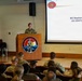 Brigadier General Stephanie Bagley, US CENTCOM DJ5, is delivering a presentation at the 163rd Regional Training Institute. She stands at a wooden podium addressing an audience of military personnel in uniform. The slide behind her identifies her name and title, and the presentation is marked 'UNCLASSIFIED'.